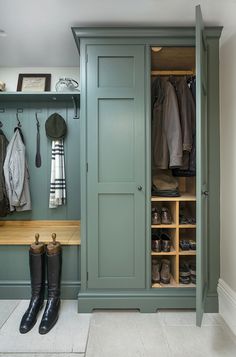 a green closet filled with lots of clothes and boots next to a wooden counter top