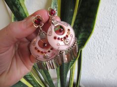 These are a funky and unique pair of vintage screw back earrings. 1960s era, these have red rhinestone centers on the earring backs and tiny rhinestone on the pink plastic hoop. The hoop has gold embellishments and dangles, lending these an ethnic look. Unfortunately the small rhinestones in the plastic part have been glued or repaired at some point and the glue is visible. Otherwise these are in great condition, but the glue is visible when worn. Priced accordingly and so AS IS. Retro Dangle Earrings For Festivals, Vintage Pink Jewelry For Festivals, Vintage Pink Metal Earrings, Vintage Pink Nickel-free Earrings, Plastic Hoop, Boho Pink, Plastic Earrings, Gold Embellishment, Ethnic Looks