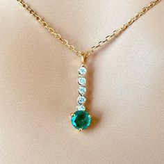 This is part of Chairish’s Fine Jewelry assortment.  The Emerald and Diamond Lariat Gold Drop Necklace Pendant features a blend of elegance and sophistication. Crafted from fourteen karats of white and yellow gold, this trending lariat necklace pendant exudes luxury. Here are the key details: Gemstones: The pendant showcases a single round emerald, bezel set and weighing 0.40 carats. The emerald exhibits a hue tone resembling grass green, adding a vibrant touch to the piece. Additionally, there Elegant Yellow Gold Lariat Necklace With Round Pendant, Elegant Yellow Gold Lariat Necklace With Gemstone, Gold Drop Necklace, Diamond Bar, Diamond Chain, Grass Green, Diamond Drops, Key Details, Lariat Necklace