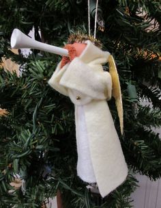 an ornament hanging from a christmas tree with a white scarf on it's back