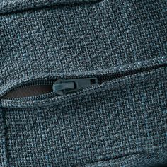 a close up view of the zipper on a blue tweed fabric material with black stitching