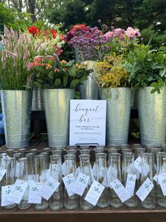 a table topped with lots of glass vases filled with flowers and cards next to each other