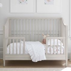 a white crib with two pictures on the wall