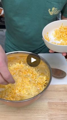 a person holding a bowl with cheese in it