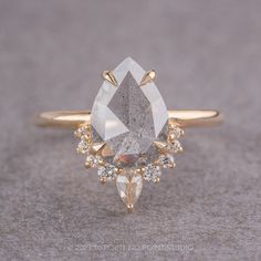 a ring with a pear shaped diamond surrounded by small white and yellow diamonds on it