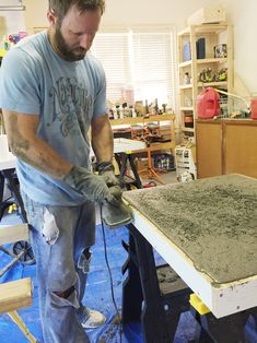 a man sanding up a table in his workshop