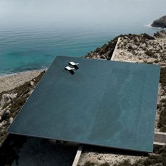 an aerial view of a house on the coast with water in the backgroud