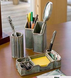 a wooden table topped with two metal containers filled with pens and pencils on top of it