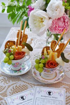 two cups filled with food sitting on top of a table next to flowers and papers