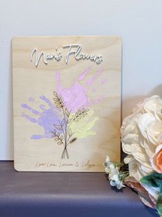 a wooden plaque with flowers on it next to a bouquet