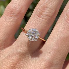 a woman's hand with a diamond ring on top of her finger, showing the center stone