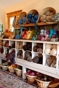 there are many yarns and baskets on the shelves in this room, including balls of yarn