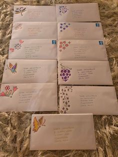 six envelopes with butterflies and flowers on them are laid out on a carpeted surface