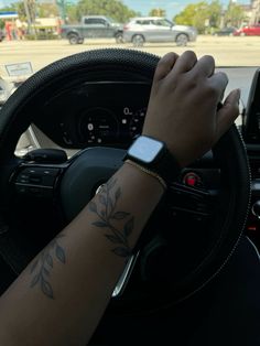 a person driving a car with their arm on the steering wheel and wristbands