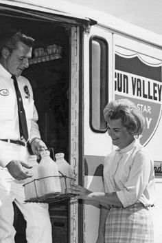 an old photo of two people getting ready to board a bus with the door open