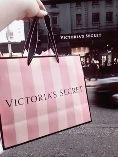 a person holding a pink victoria's secret shopping bag