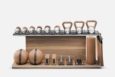 an assortment of kettles, dumbbells and other items on a wooden shelf