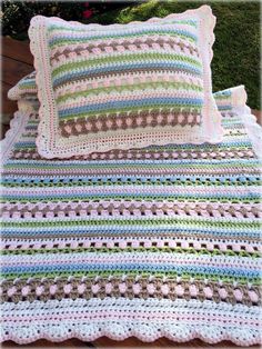 a crocheted blanket and pillow sitting on top of a wooden bench