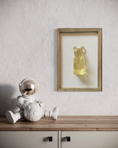 an astronaut's teddy bear sitting on top of a wooden table in front of a framed photograph