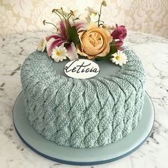 there is a blue cake with flowers on the top that says detosa in front of it