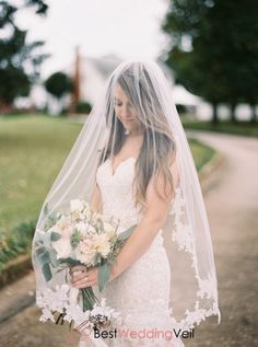 a woman in a wedding dress is holding a bouquet and posing for the camera with her veil over her head