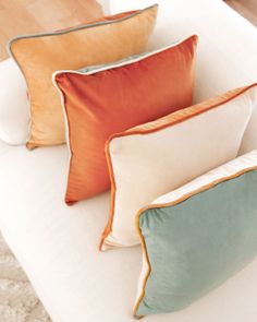 three different colored pillows sitting on top of a white couch