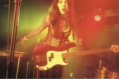 a woman standing in front of a bass guitar on top of a stage next to a microphone