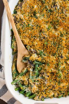 a casserole dish filled with green beans and mushrooms, topped with a wooden spoon