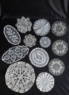 several crocheted doily patterns on a black tablecloth with white laces