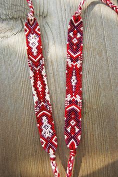 two red and white beaded necklaces sitting on top of a wooden table