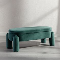 a green bench sitting on top of a hard wood floor next to a white wall