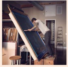 a man standing on top of an easel in a room with bookshelves