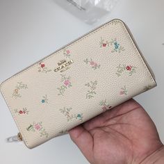 a woman's hand holding a white purse with flowers on the front and side