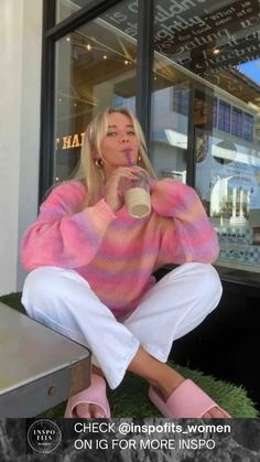 a woman sitting on the ground drinking from a cup and wearing pink slip - ons