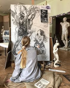 a woman sitting in front of a drawing on a easel with her hair pulled back