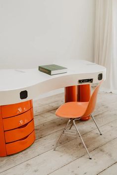 an orange chair sits next to a white desk