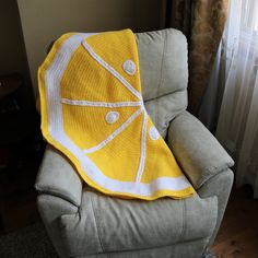 a yellow and white blanket sitting on top of a gray couch next to a window