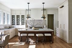 a large kitchen with white cabinets and wooden flooring, along with an island in the middle