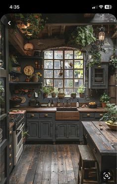 an old fashioned kitchen with wooden floors and lots of greenery on the windowsill