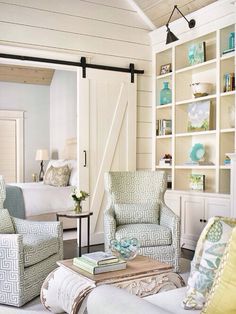 a living room filled with white furniture and lots of books on top of a book shelf