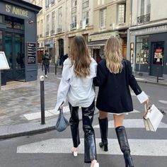 two women walking down the street carrying shopping bags