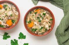 two bowls of chicken noodle soup with carrots and parsley