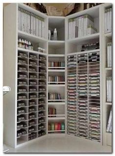 a white bookcase filled with lots of books next to a wall full of binders