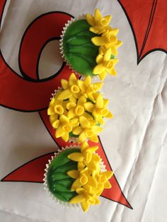 two cupcakes decorated with yellow flowers and green leaves