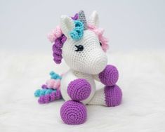 a crocheted unicorn sitting on top of a white blanket