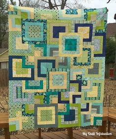 a green and yellow quilt on a wooden bench