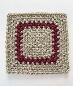 a crocheted square with a red and white design on the center is shown