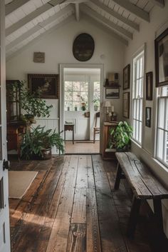 a wooden bench sitting in the middle of a room next to a door and windows