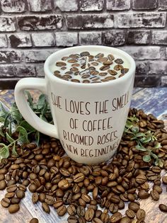 coffee beans and leaves are scattered around a mug with the words she loves the smell of coffee bloomed roses, new beginnings