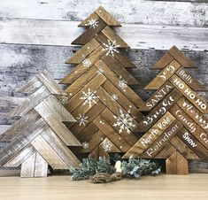 three wooden christmas trees with white snowflakes on them and one is made out of wood planks